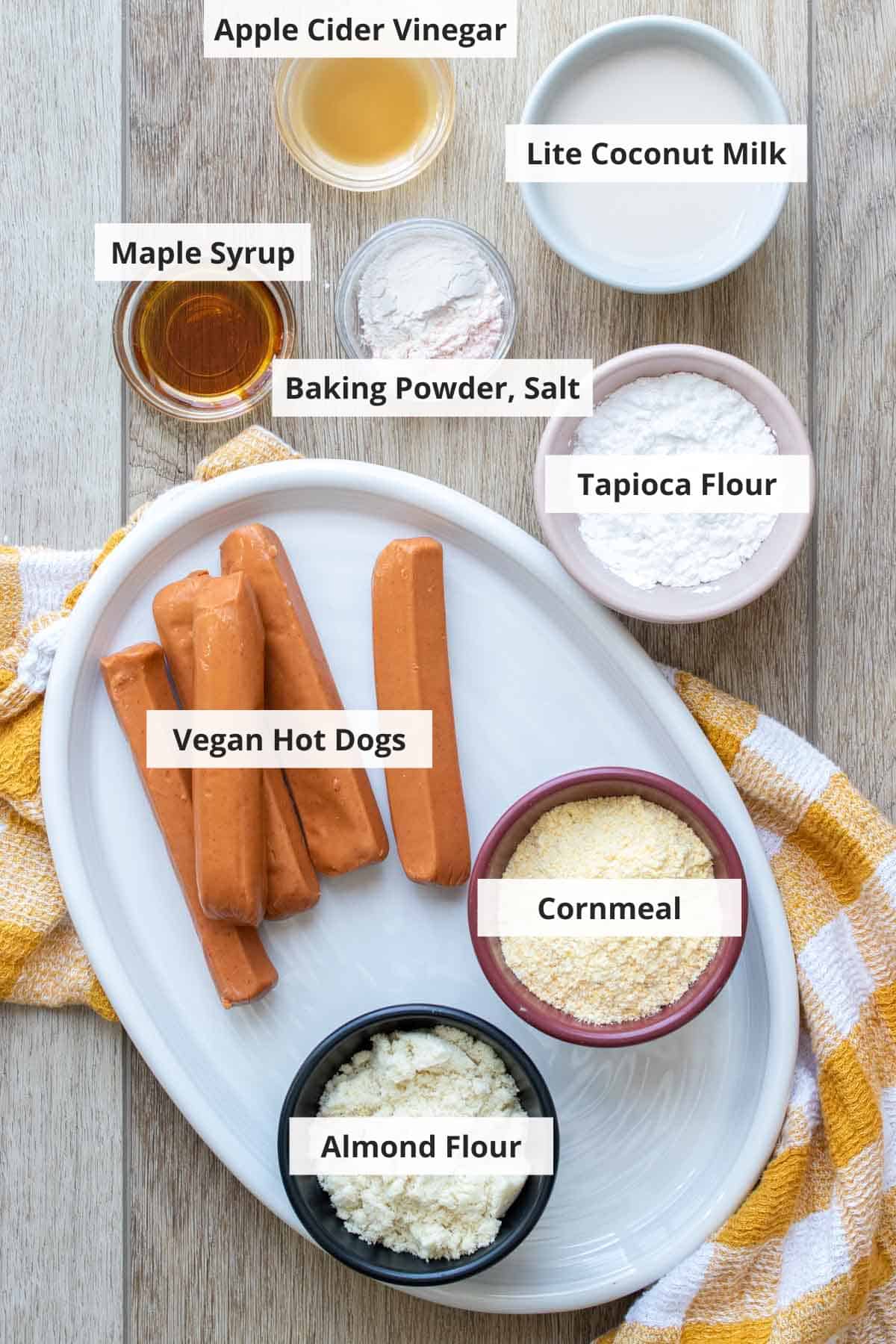 Ingredients for healthy baked vegan corn dogs on a light wood background.