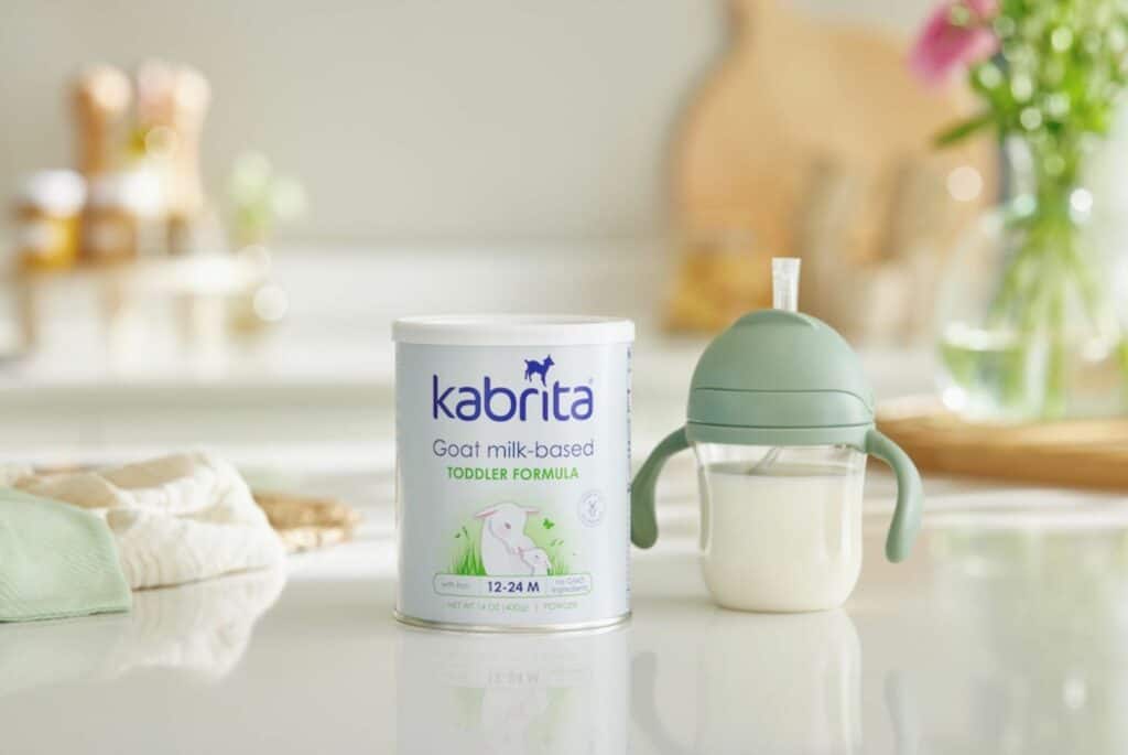 Can of Kabrita Goat Milk Toddler Formula next to sippy cup filled with formula on a countertop.