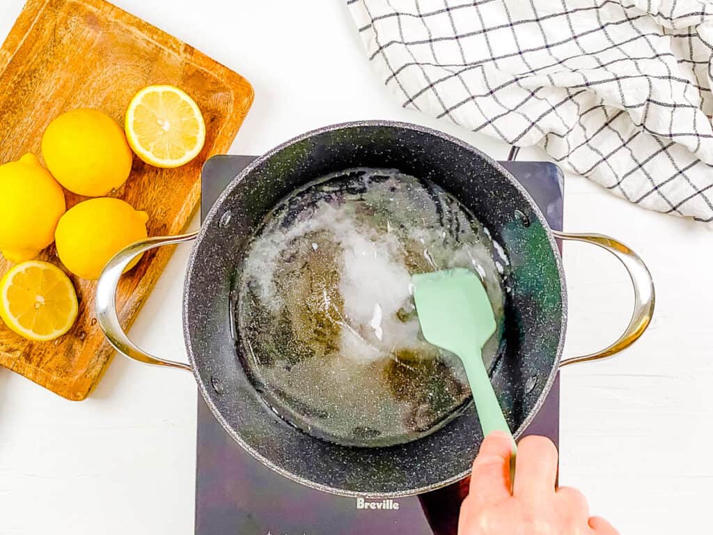 Lemon juice added to sugar and water in a saucepan on the stove.
