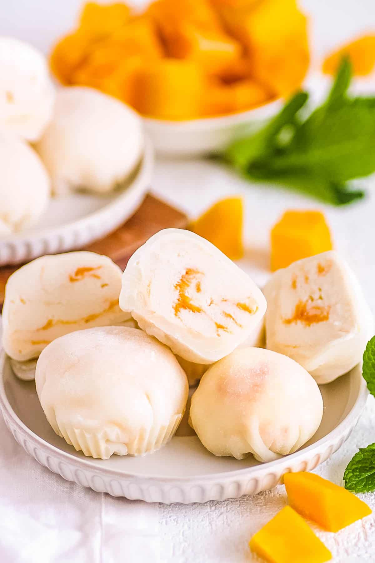 Mango mochi stacked on a white plate.