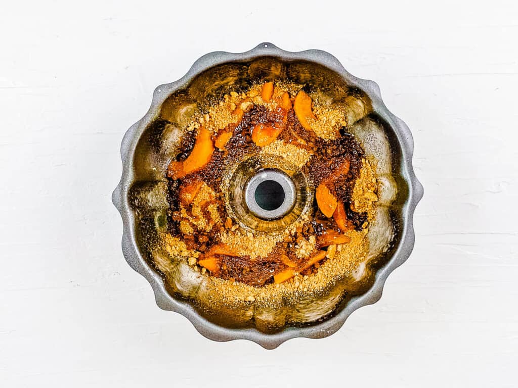 Peaches, brown sugar and butter in the bottom of a bundt baking pan.