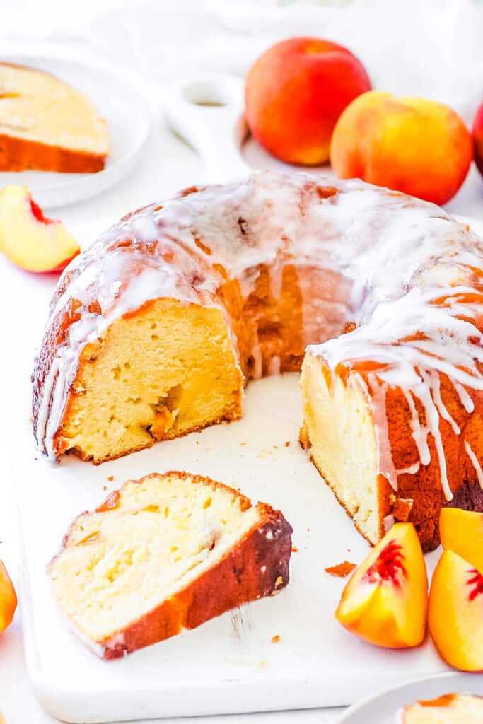 Peach cobbler pound cake served on a white tray with fresh peaches on the side.