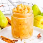 Spiced pear compote in a glass jar with a spoon.