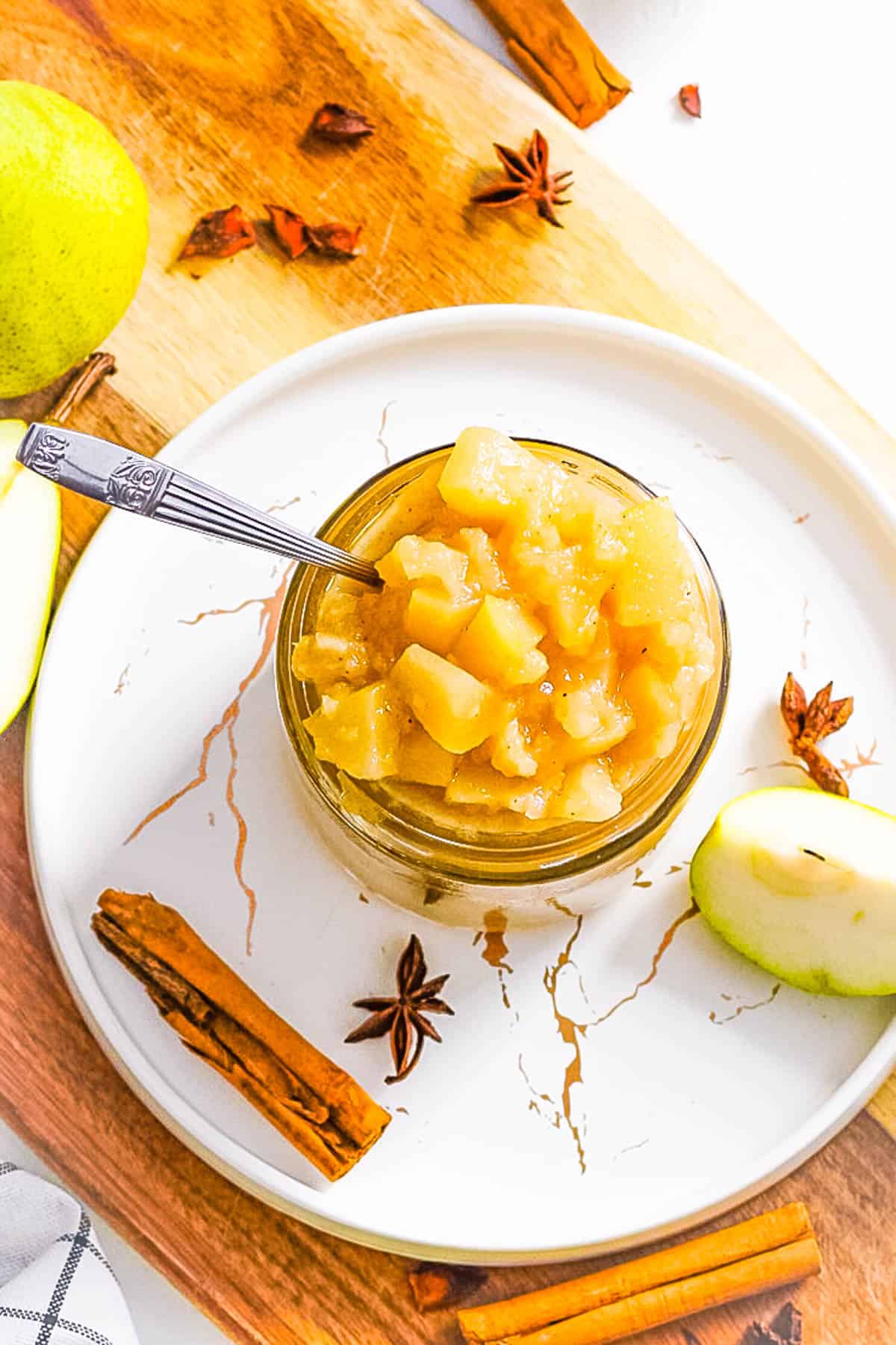 Cinnamon pear compote preserves in a glass jar with a spoon.
