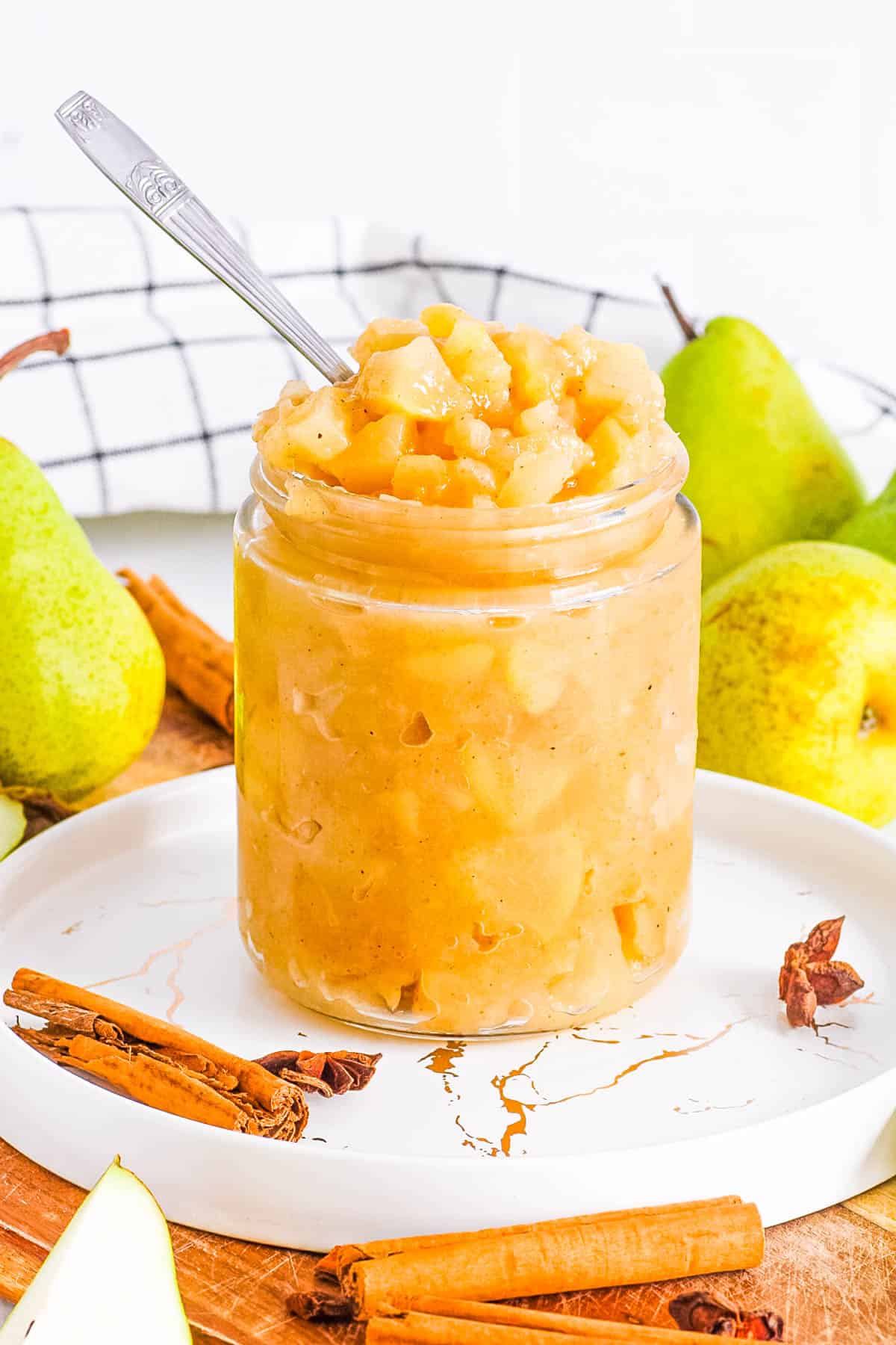 Spiced pear compote in a glass jar with a spoon.