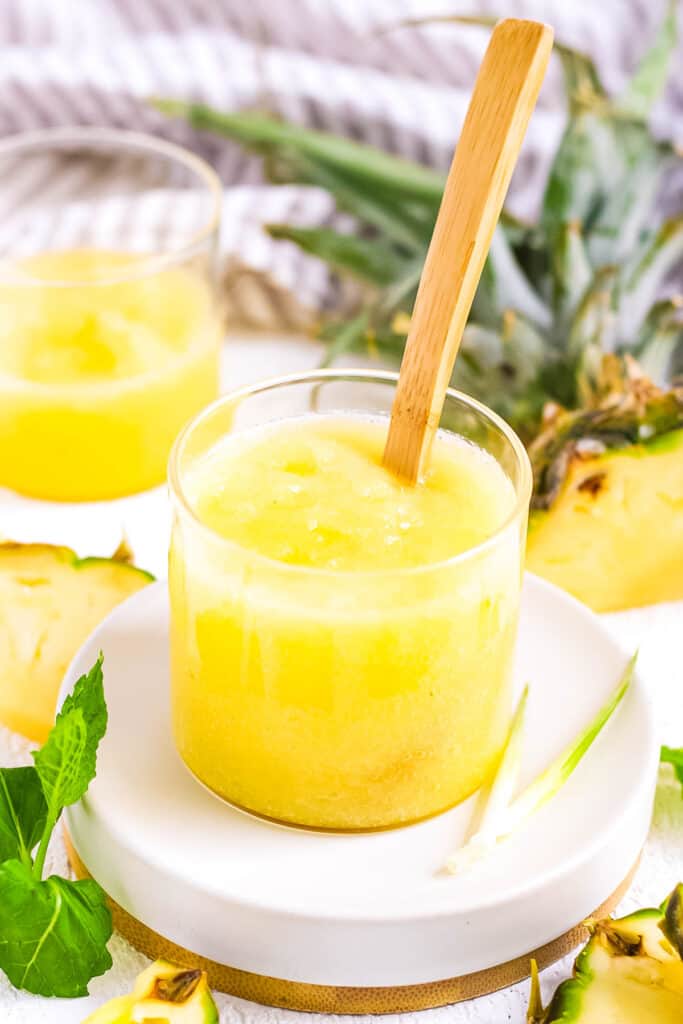 Pineapple puree baby food served in a glass jar with a wooden spoon.