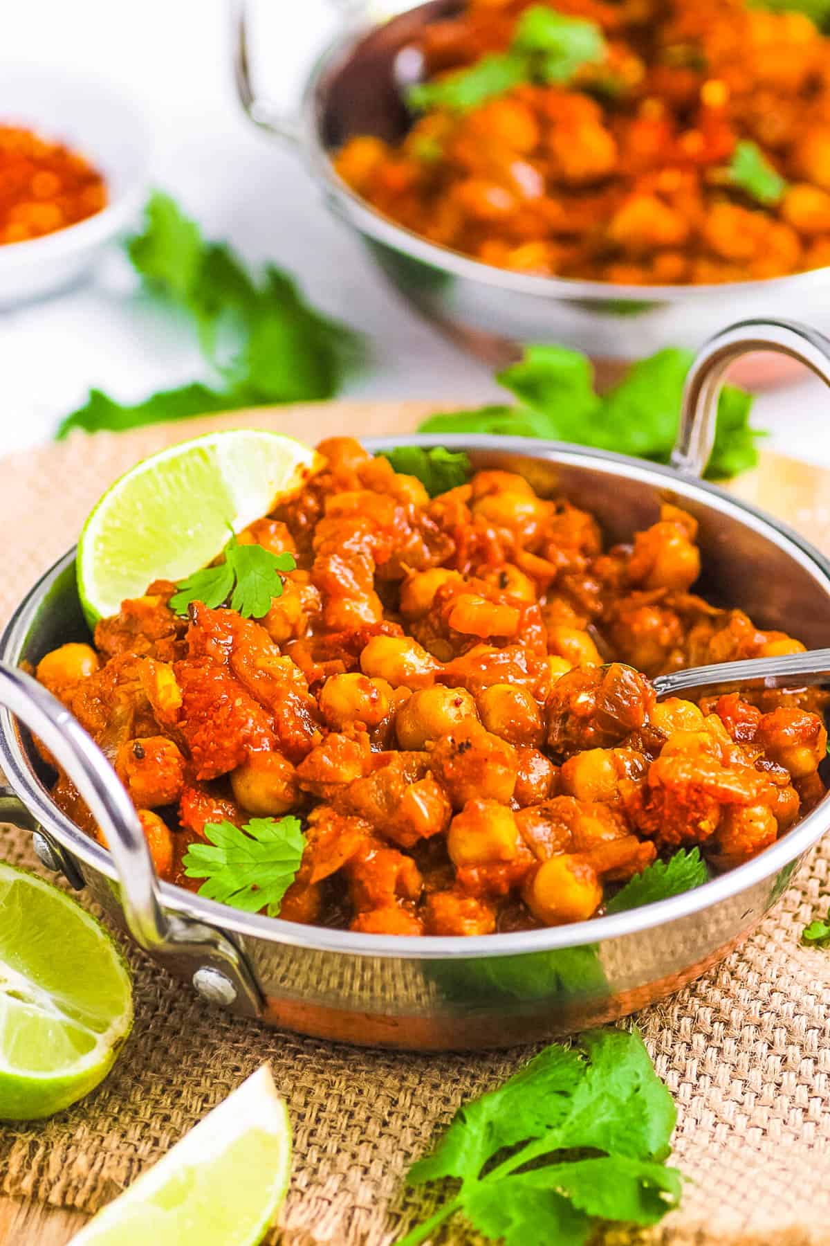 Homemade easy chole masala served in a stainless steel bowl garnished with cilantro and lime.