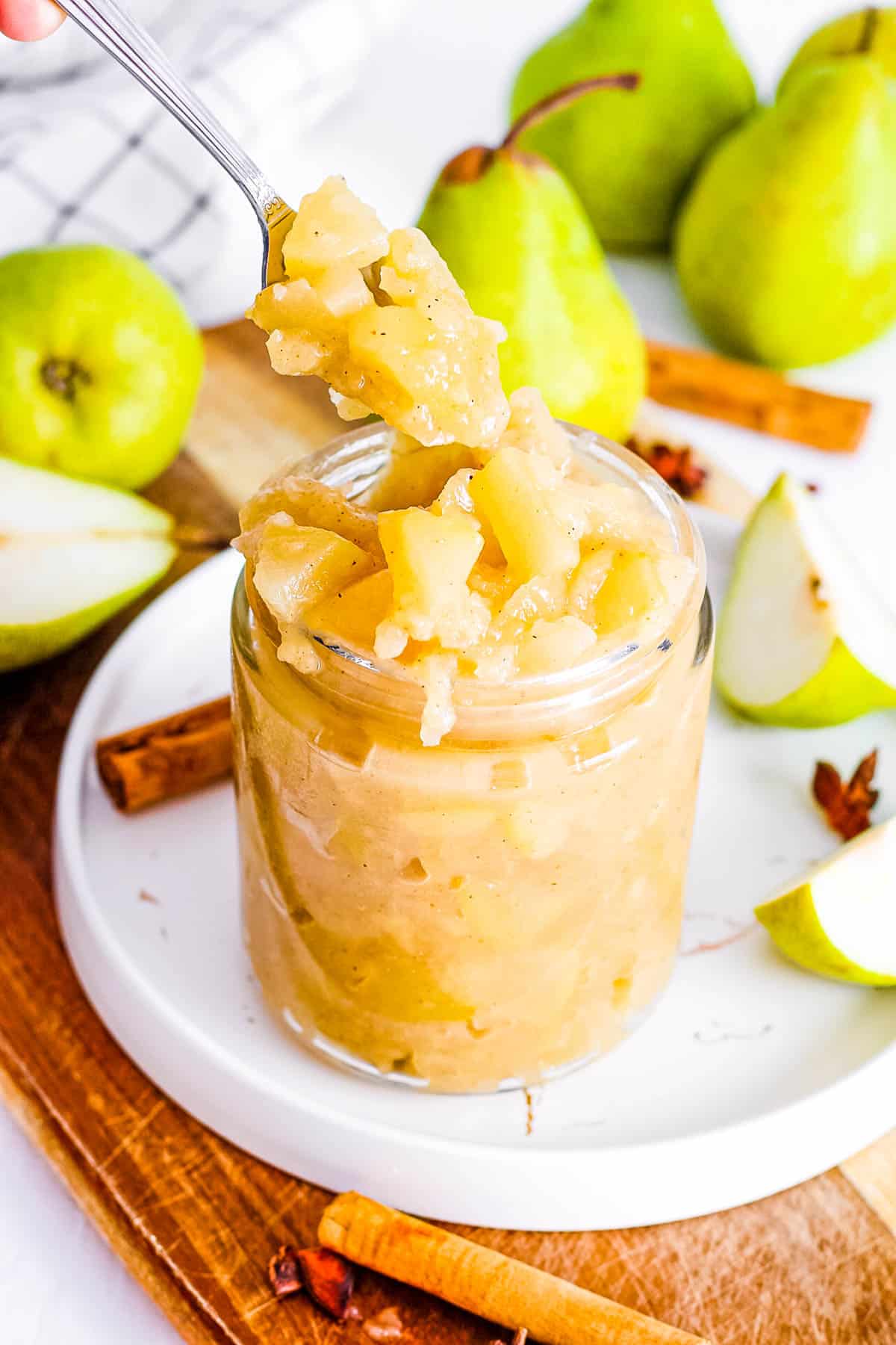 Healthy pear compote in a glass jar with a spoon.