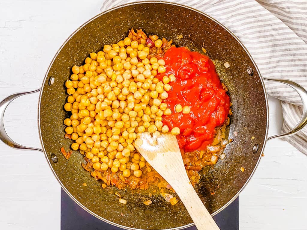 Chickpeas and tomatoes simmering in a pot on the stove.