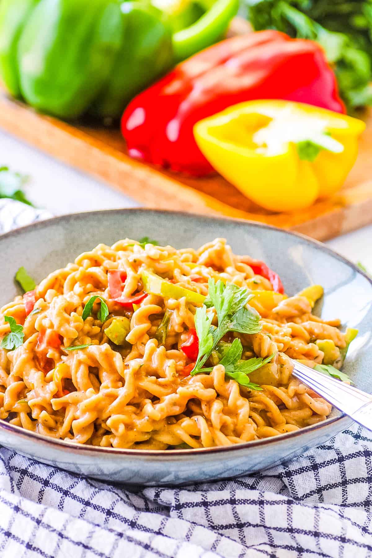 Vegan rasta pasta served in a blue bowl with a fork.