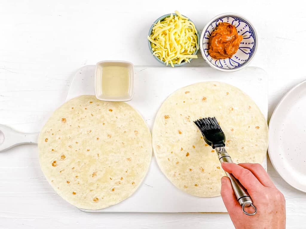 Tortillas brushed with olive oil on a cutting board.