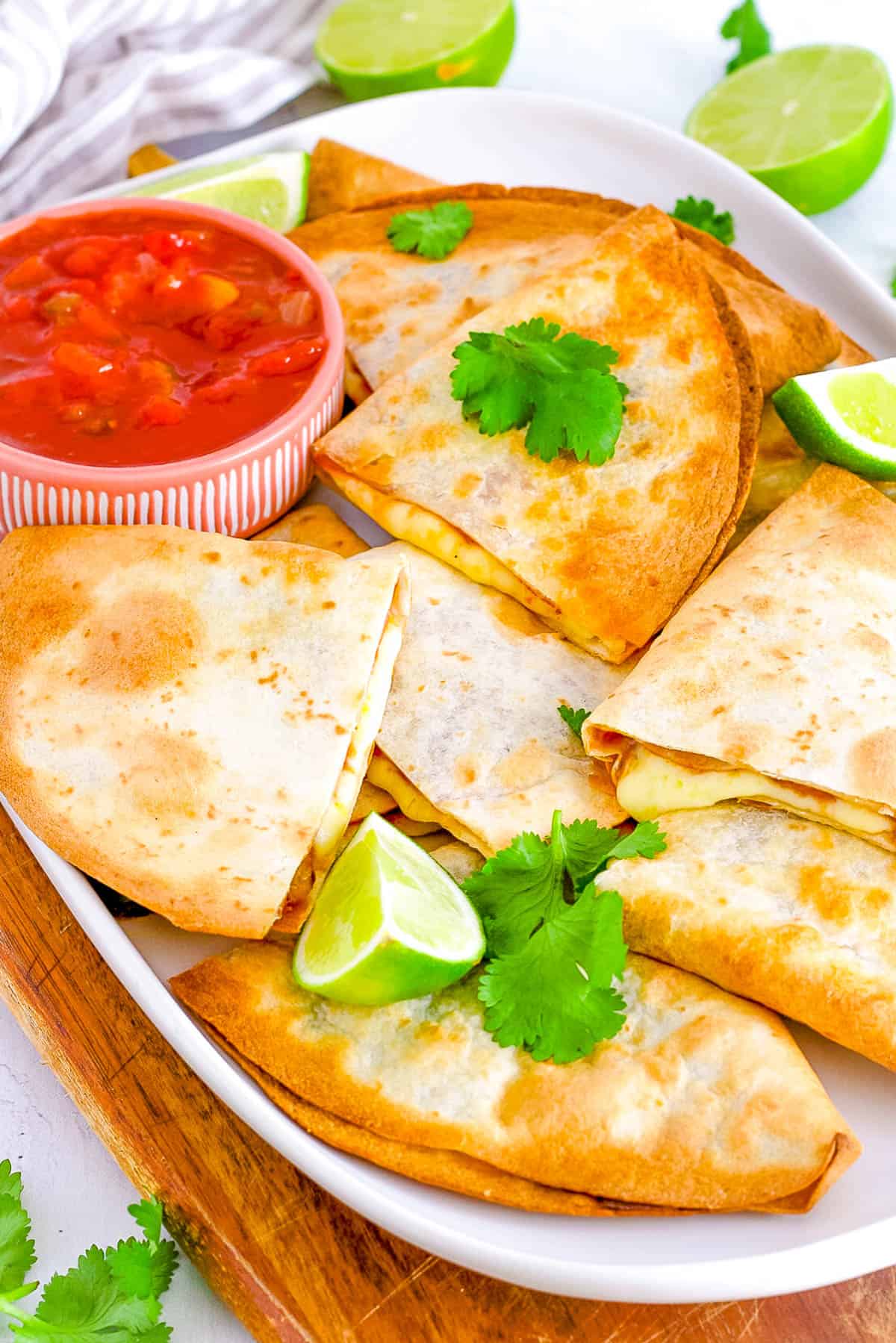 Vegetarian air fryer quesadillas served on a white platter with salsa on the side.