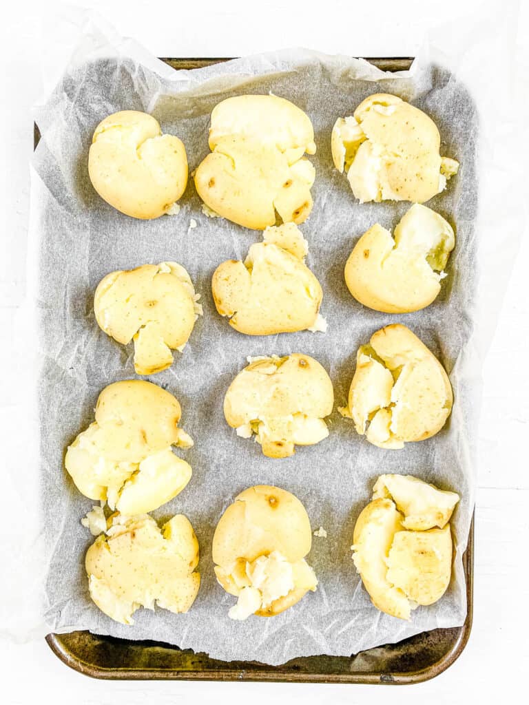 Smashed baby potatoes on a baking sheet.