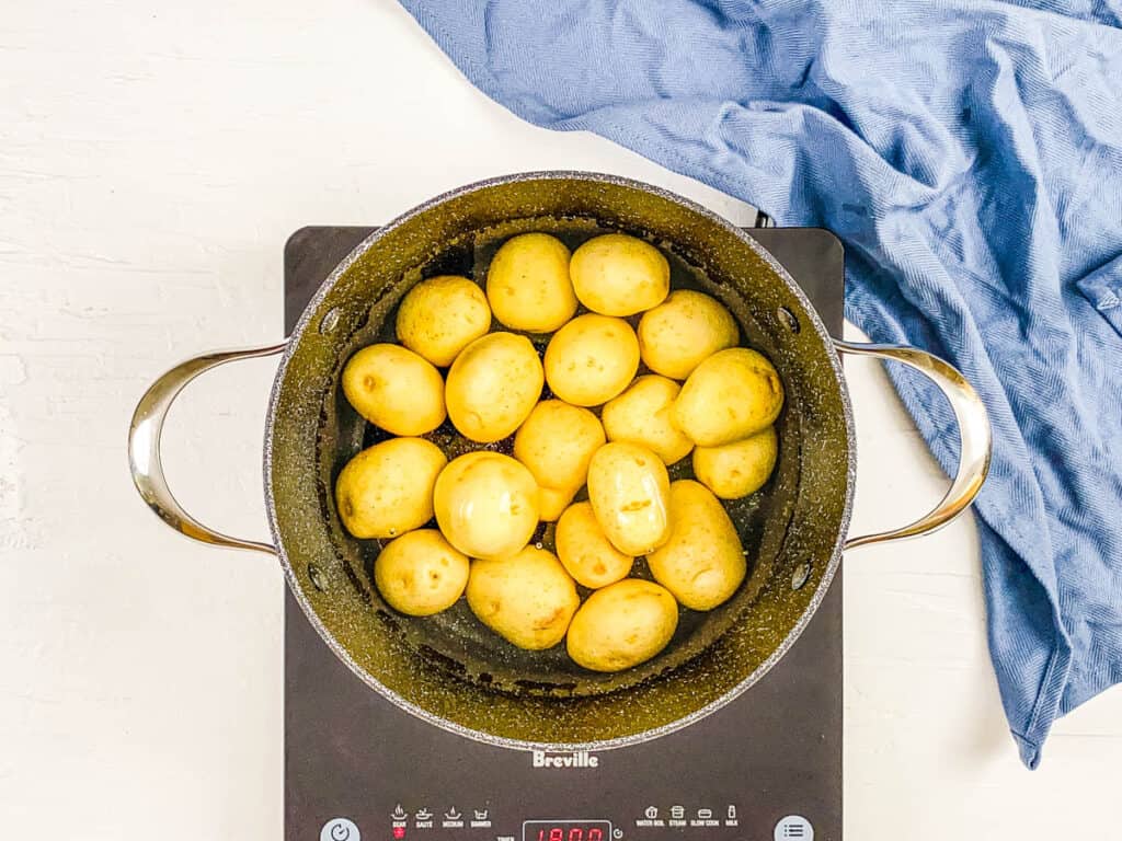Potatoes boiling in a stock pot on the stove.