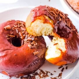Eggless donuts, glazed with chocolate glaze, served on a white plate.