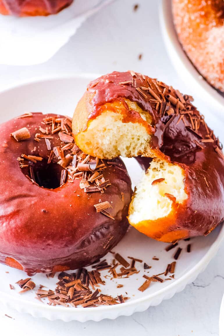 Eggless donuts, glazed with chocolate glaze, served on a white plate.