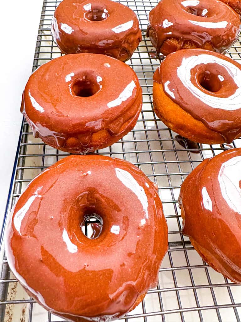 Doughnuts glazed with a chocolate glaze, cooling on a wire rack.
