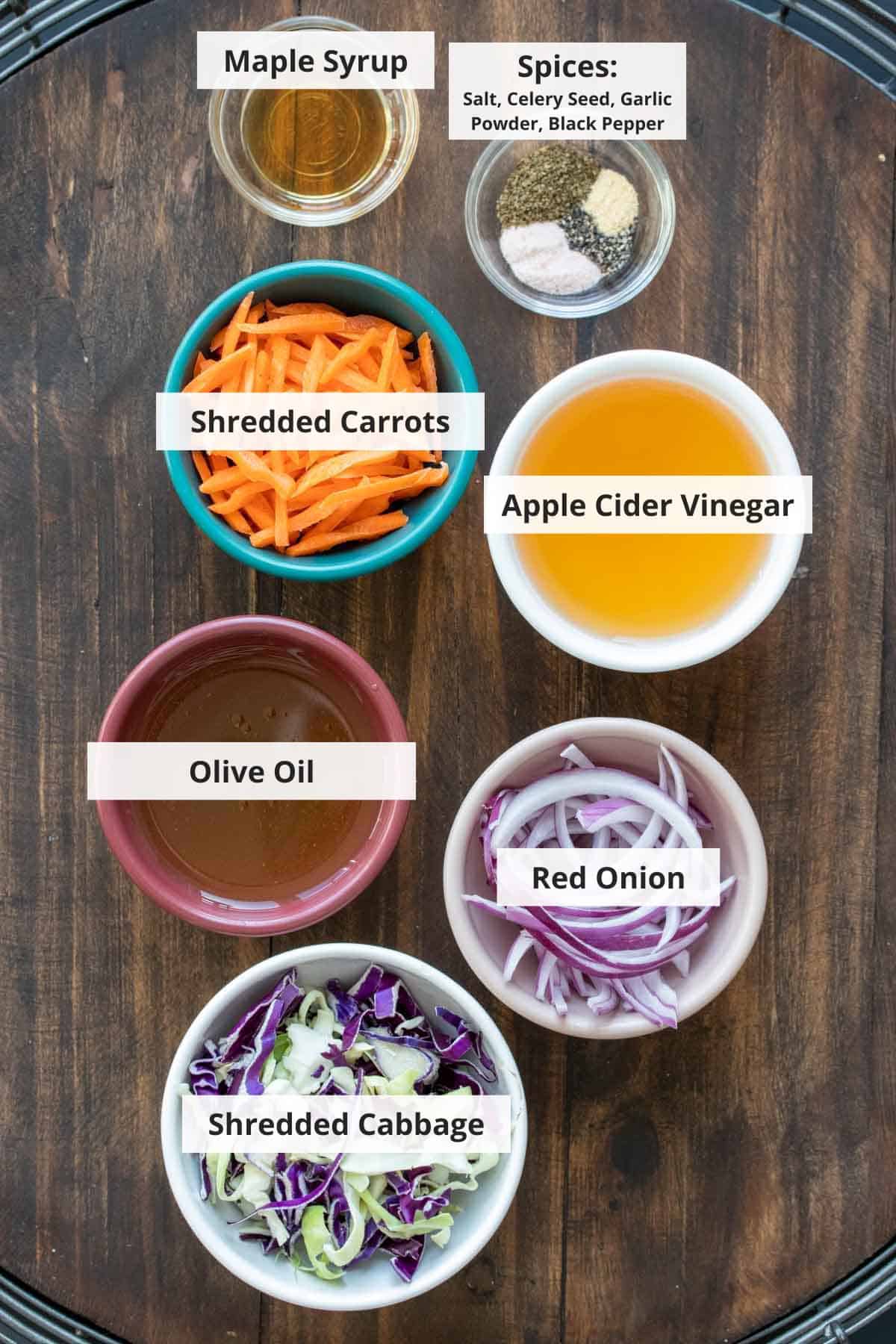 Ingredients for apple cider vinegar coleslaw on a wood background.