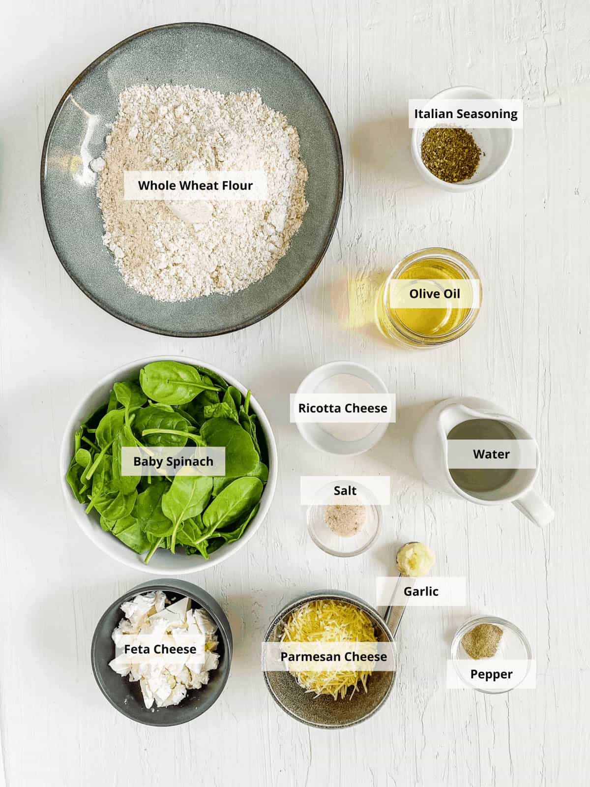 All of the ingredients for spinach pizza on a white background.