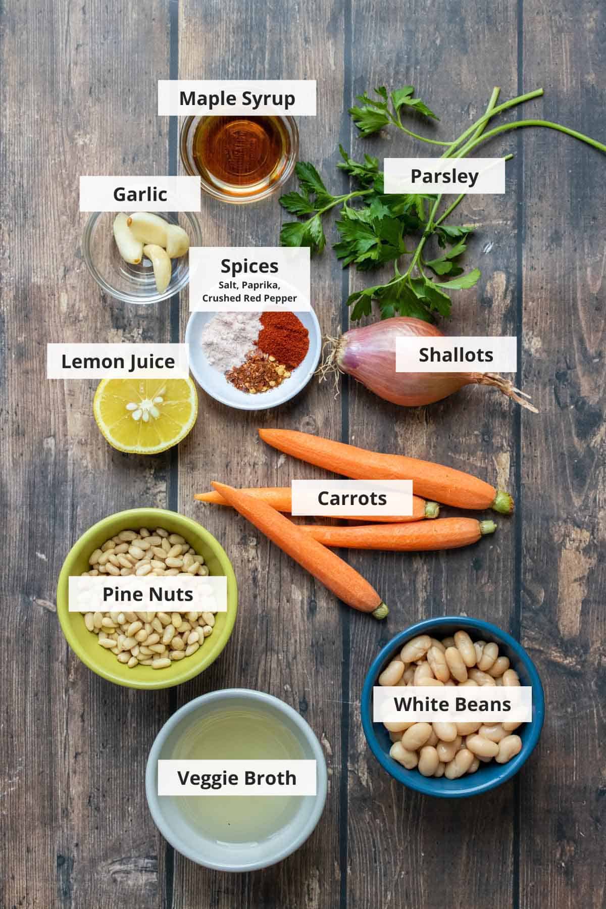 Ingredients for roasted carrot hummus recipe on a wood background.