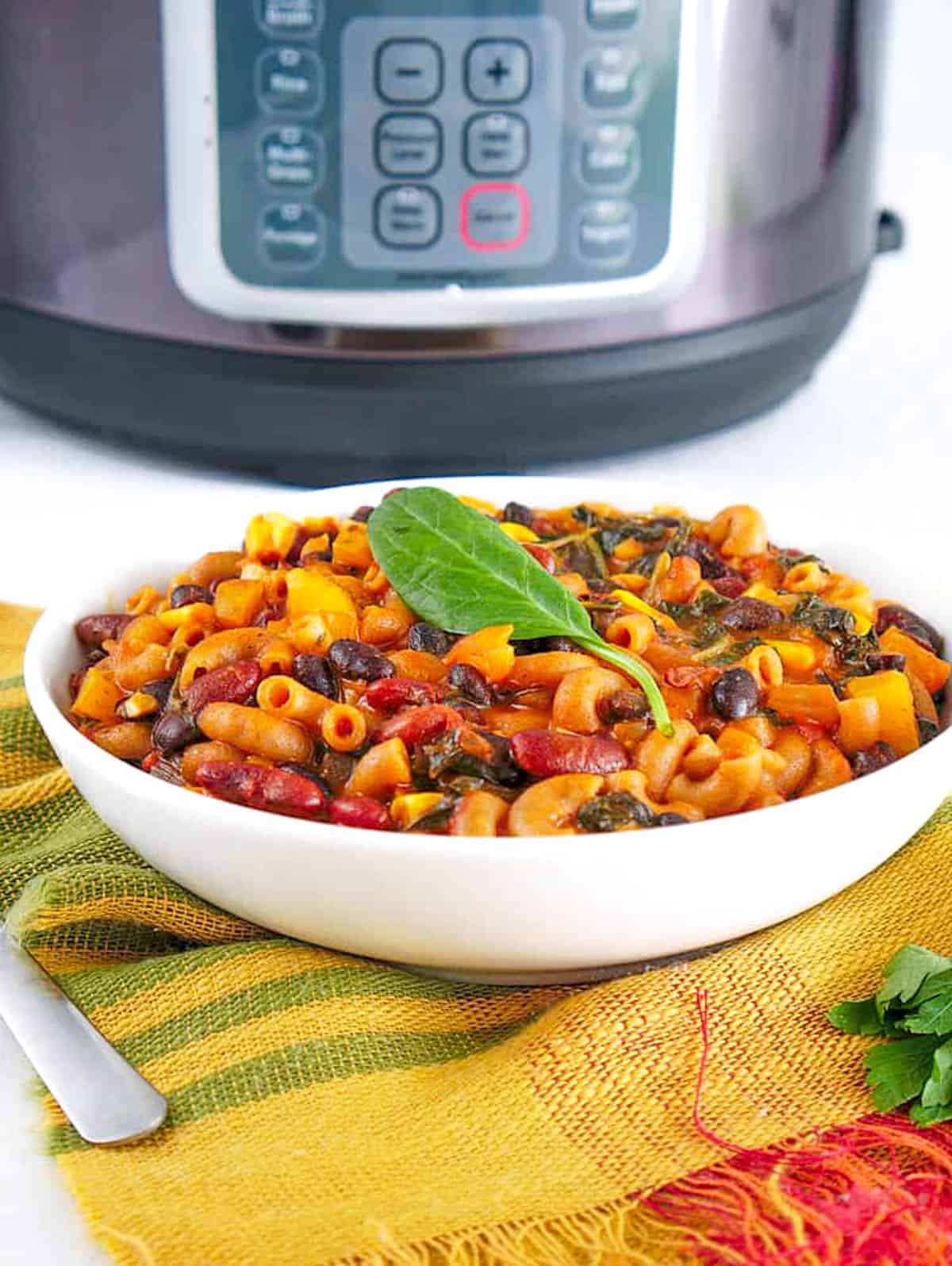 Instant Pot chili mac and cheese served in a white bowl with an instant pot in the background. 