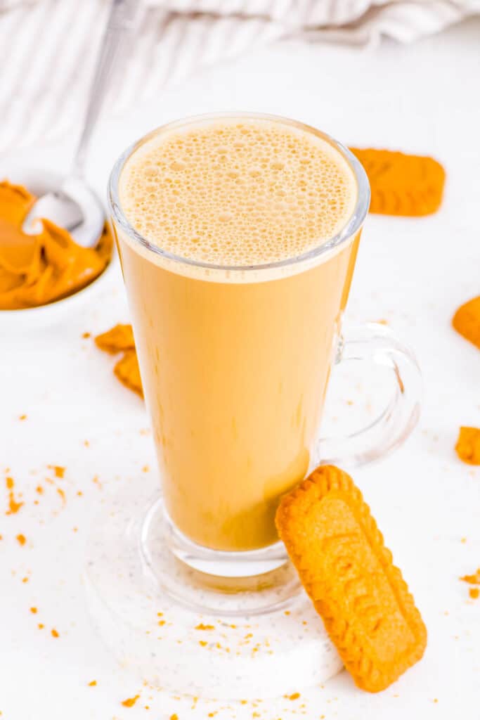 Biscoff coffee served in a glass with a Lotus Biscoff cookie on the side.