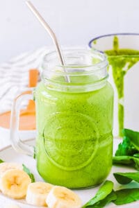 Easy spinach and banana smoothie with peanut butter served in a mason jar glass with a straw.