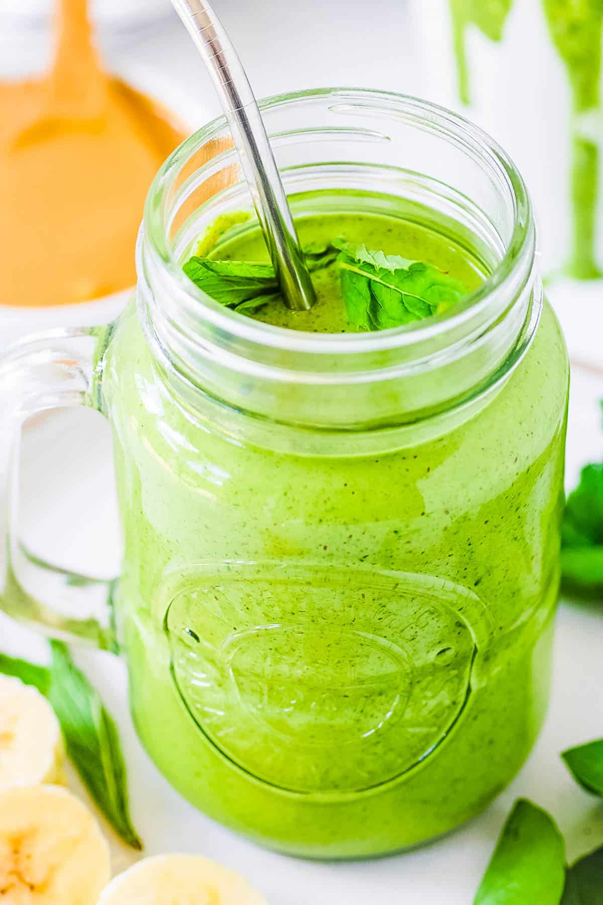 Healthy spinach and banana smoothie with peanut ،er served in a mason jar gl، with a straw.