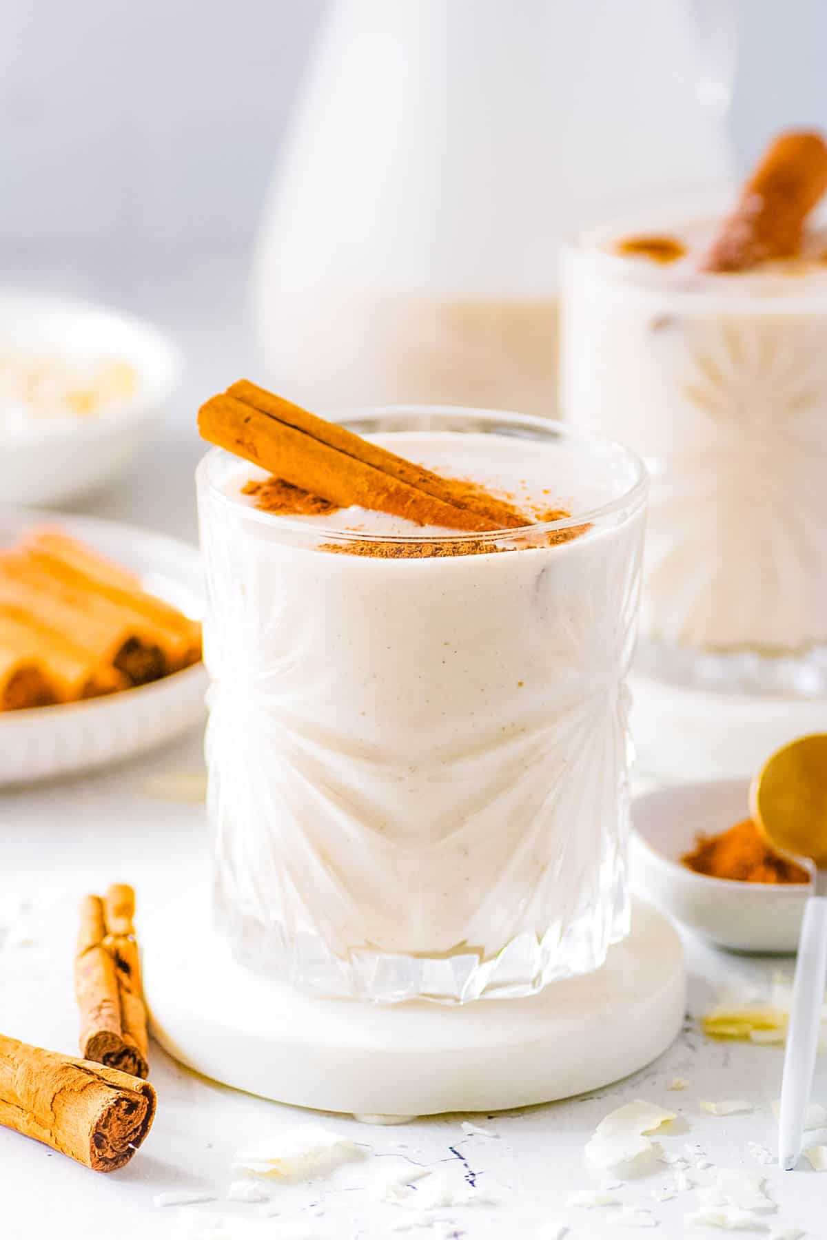 Vegan coquito served in a glass with a cinnamon stick as a garnish.