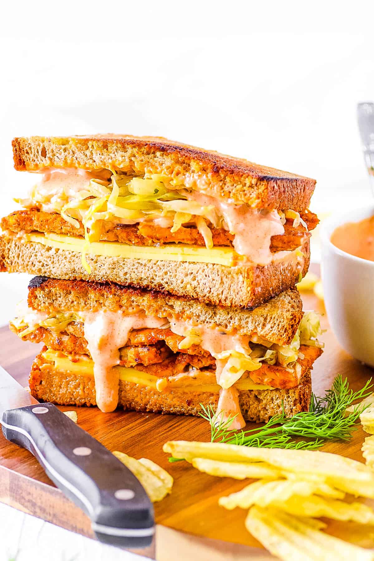 Vegan reuben sandwich stacked on a cutting board.