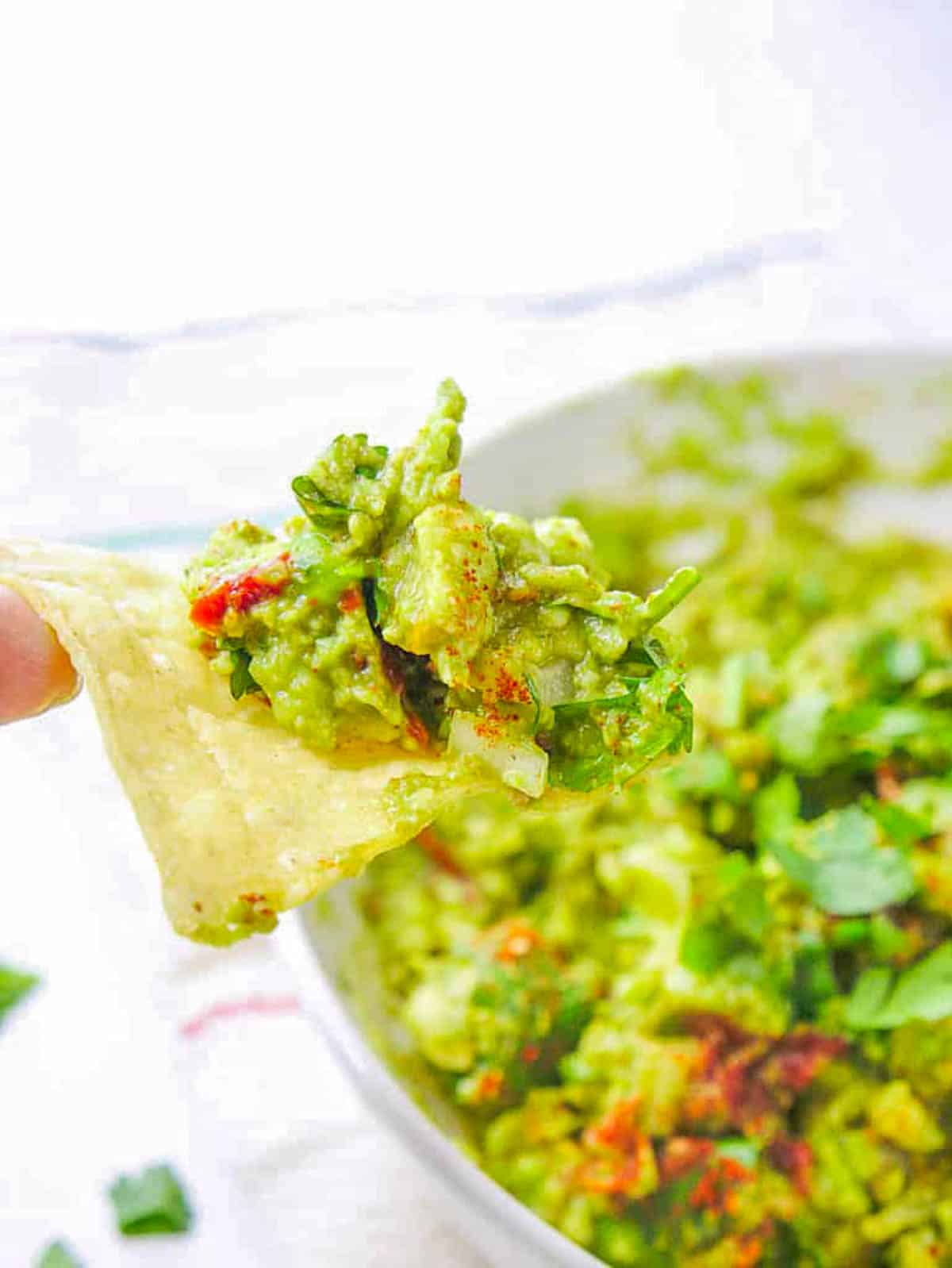 Tortilla chip with low calorie guacamole on it, ready to be eaten.