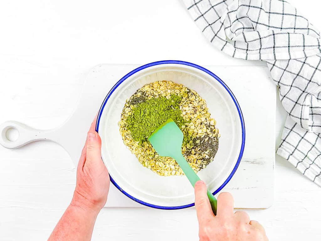 Matcha powder, oats, and ،es mixed in a mixing bowl.