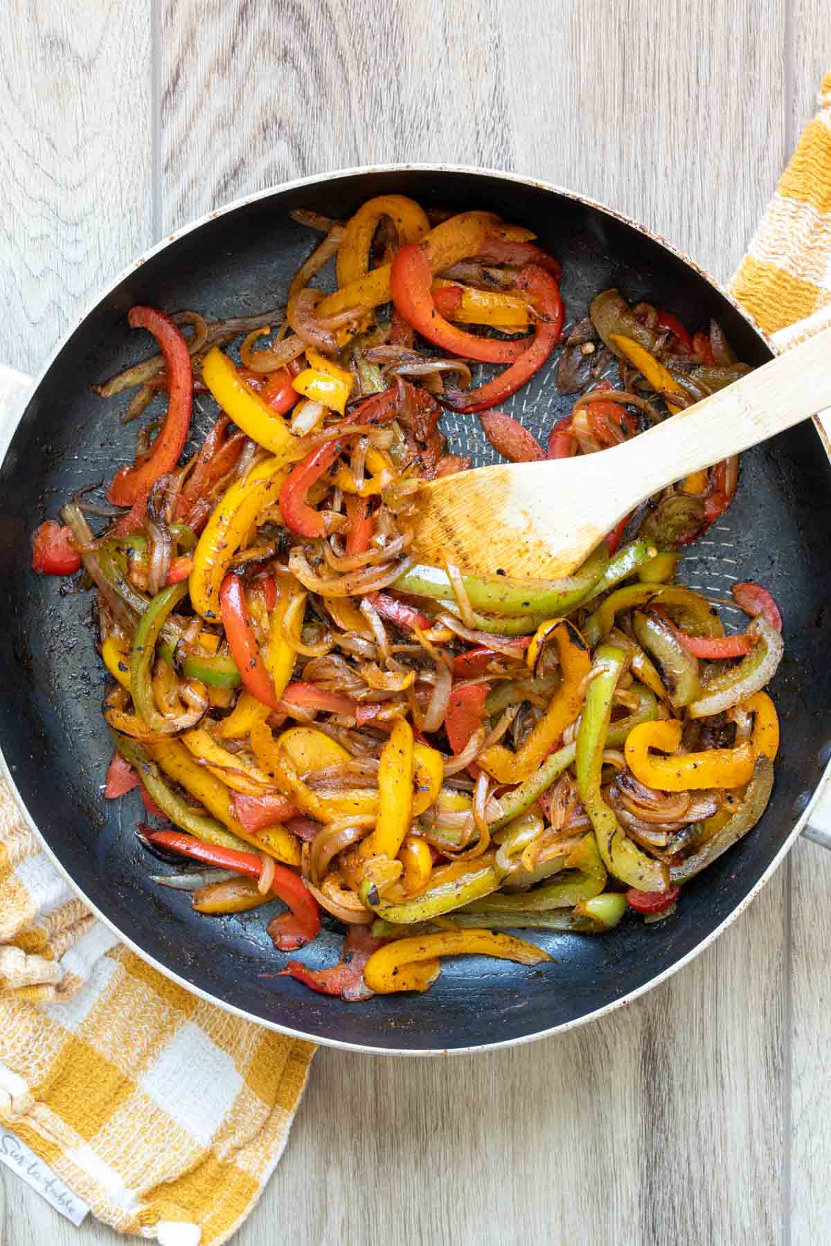 Peppers and onions sauteeing in a pan.