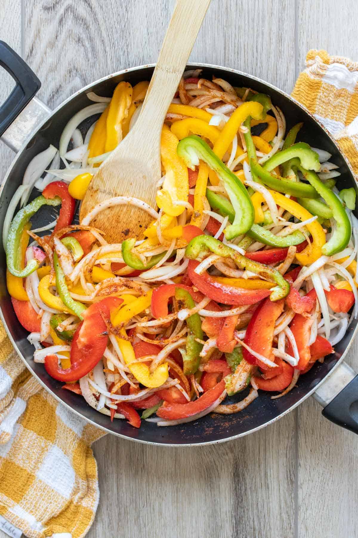 Peppers and onions sauteeing in a pan.