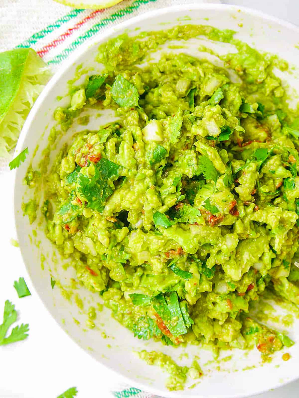 Healthy guacamole served in a bowl with a tortilla chip garnish.