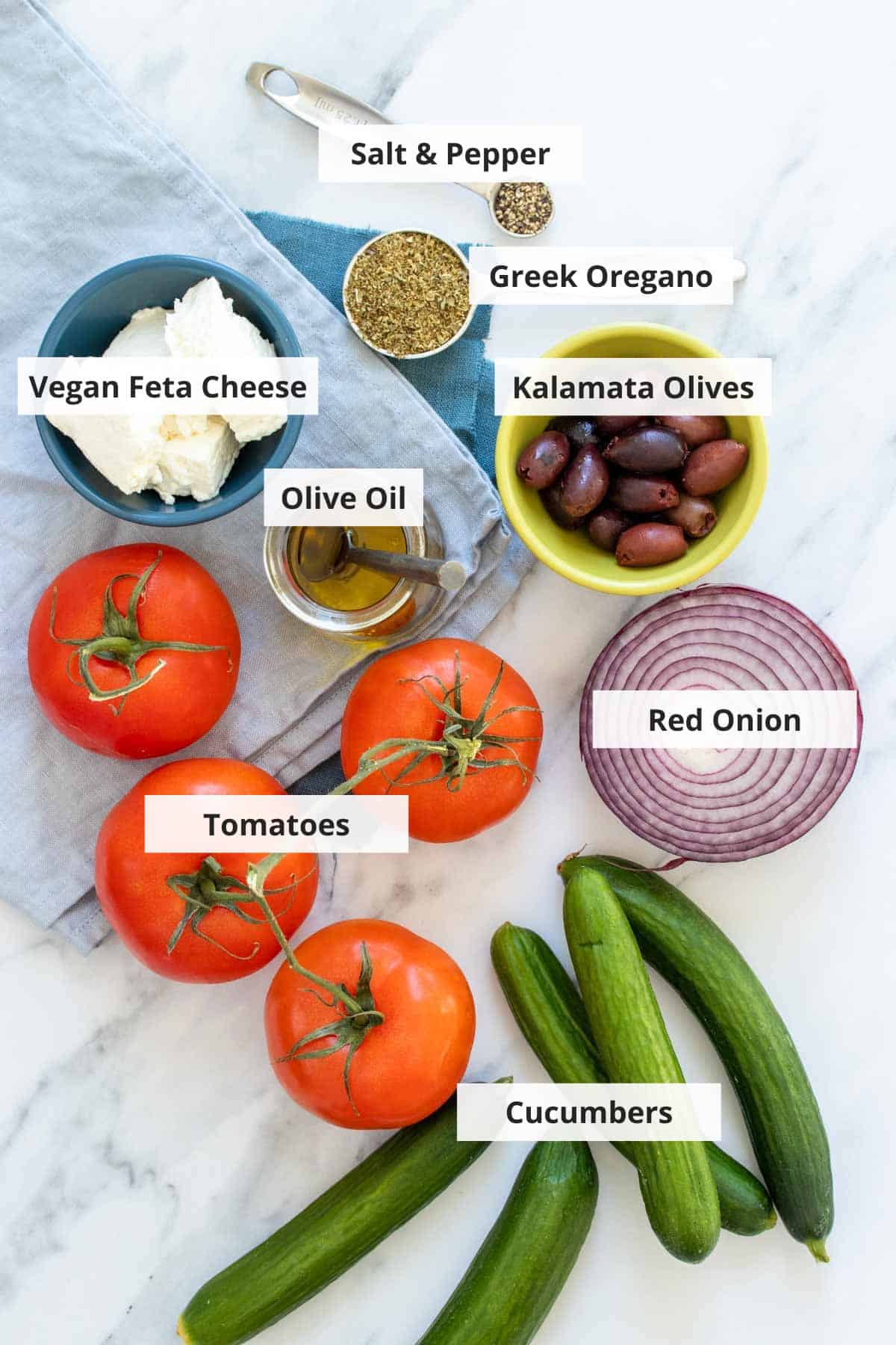 Ingredients for vegan Greek salad recipe on a white countertop.