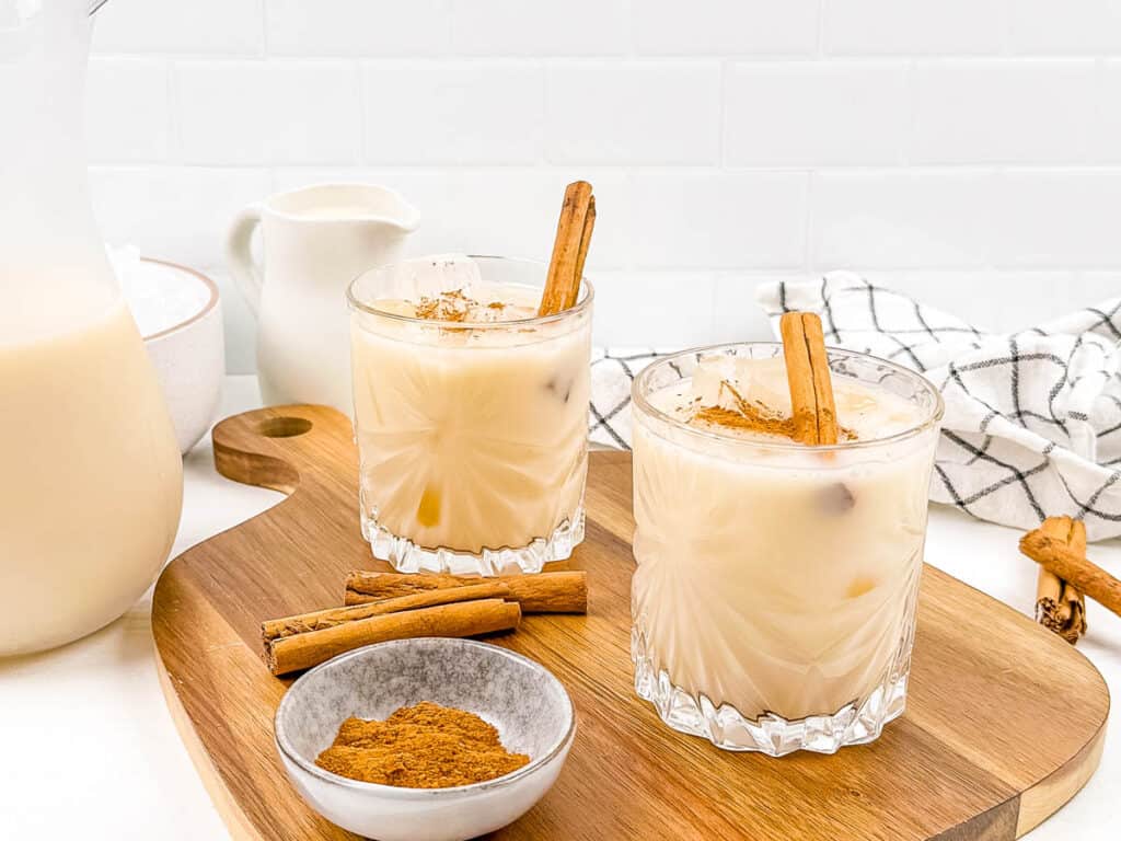 Homemade non dairy horchata served in glasses with ice and cinnamon sticks.
