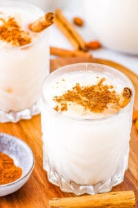 Vegan horchata served in glasses with ice and cinnamon sticks and ground cinnamon as a garnish.
