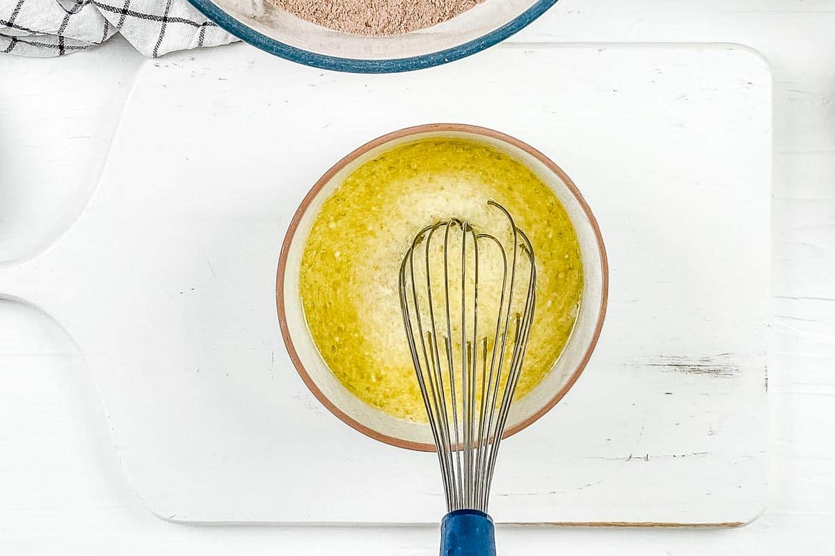 Mixing the wet ingredients together in a small mixing bowl, on a white background. 