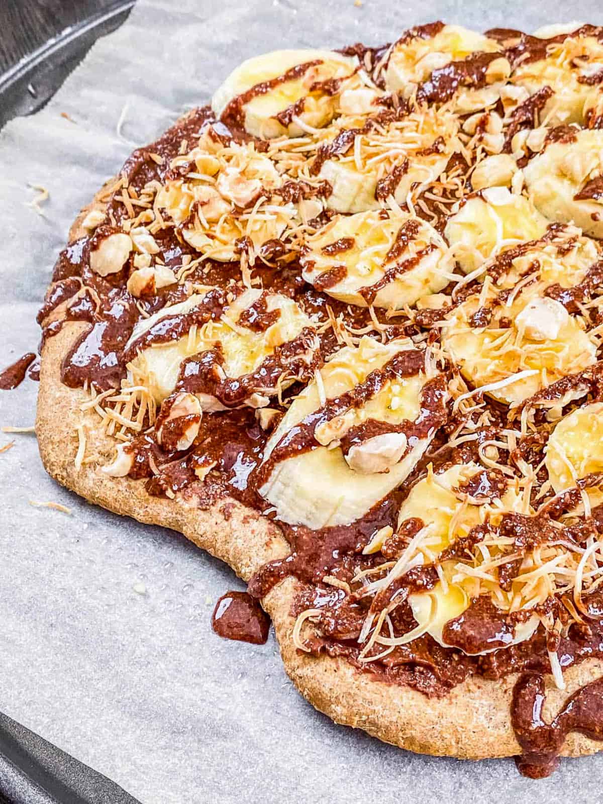 Closeup of banana Nutella pizza (dessert pizza recipe) on parchment paper.