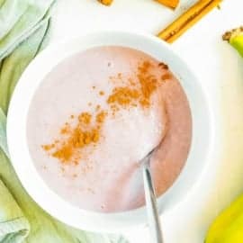 Jamaican banana porridge, served in a white bowl, garnished with a sprinkle of cinnamon on top.