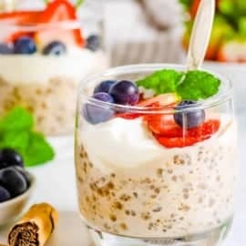 Vegan high protein overnight oats served in glasses with fresh berries and mint as a garnish.