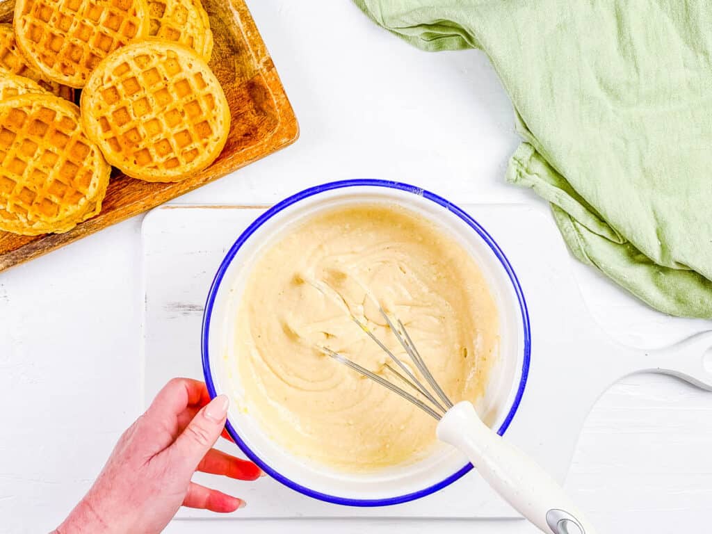 Waffle batter being whisked in a mixing bowl.