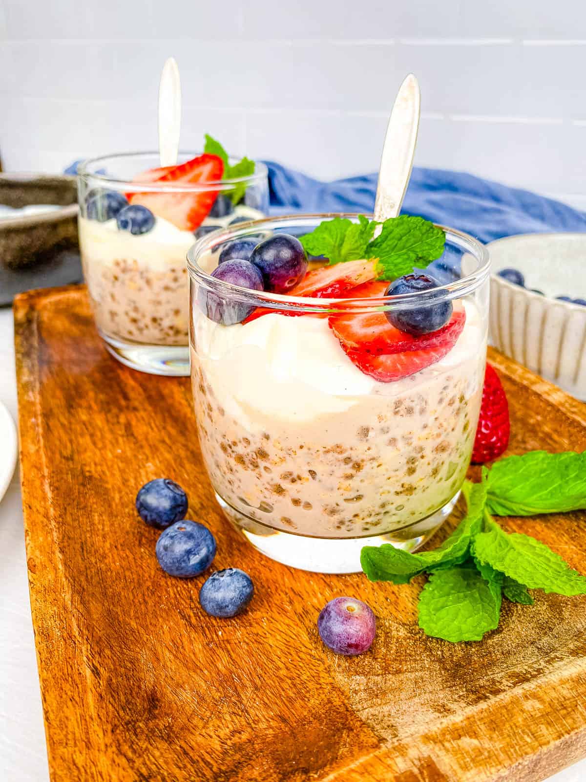 Healthy high protein overnight oats served in glasses with fresh berries and mint as a garnish.