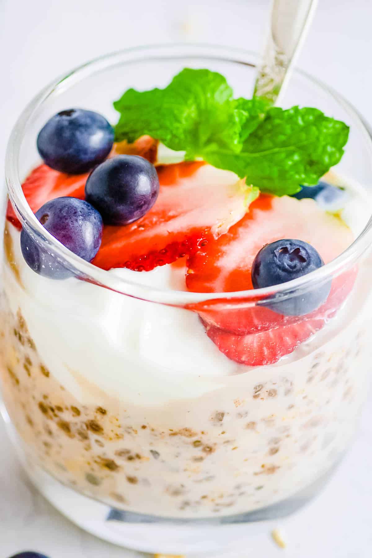 High protein overnight oats served in glasses with fresh berries and mint as a garnish.