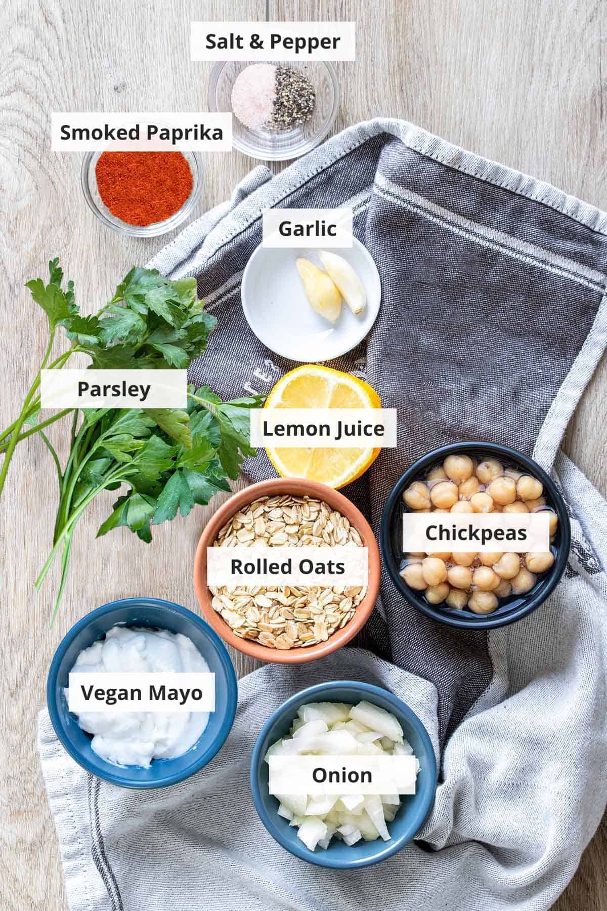 Ingredients for vegan chickpea burgers on a light wood background.