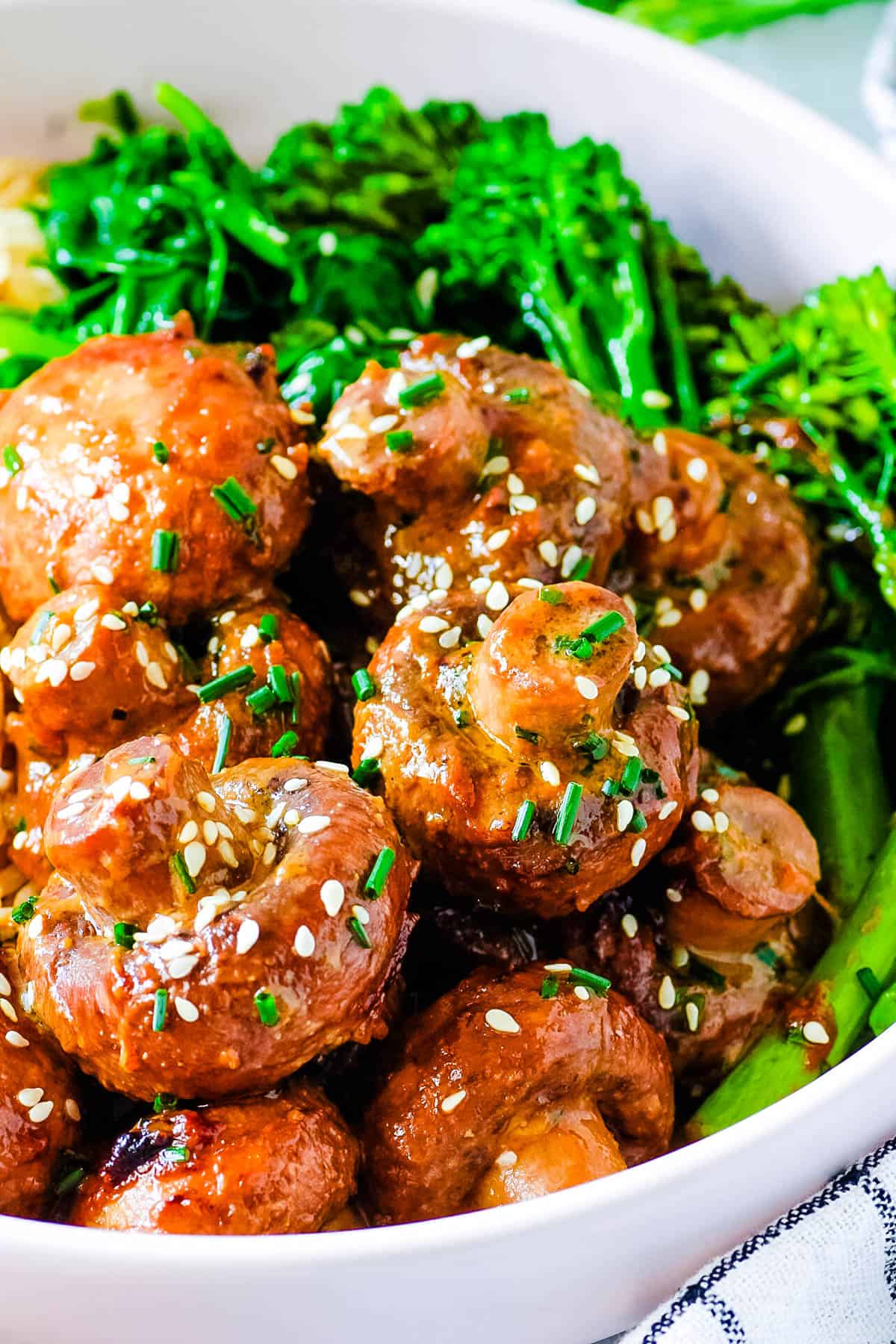 Miso mushrooms tossed with garlic miso ،er, served in a white bowl with brown rice and fresh greens on the side.