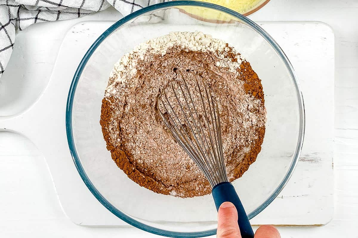 Whisking together the dry ingredients in a large mixing bowl, on a white background. 