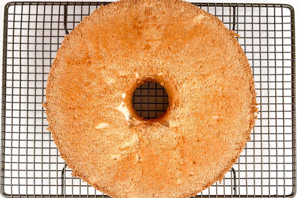 Angel food cake cooking on a wire rack on a white background.