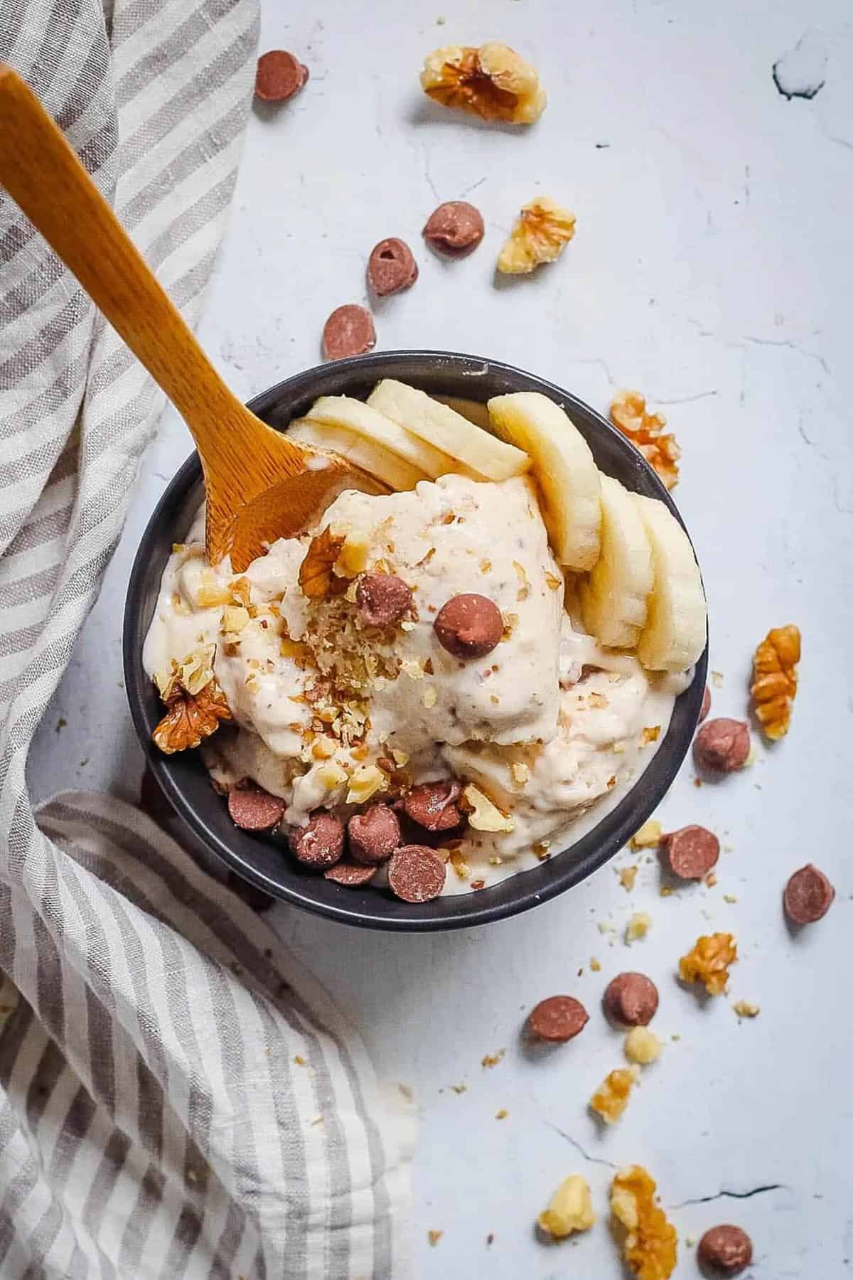 Chocolate banana ice cream in a black serving bowl with chocolate chips on top.